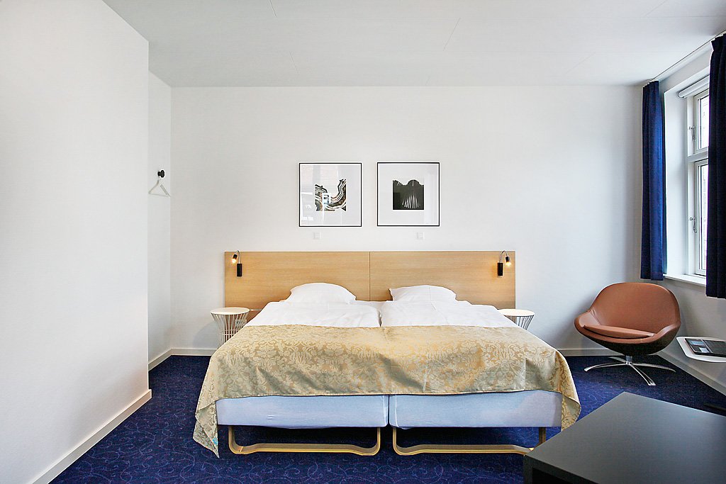 Juniorsuite med dobbelte senge og lænestol ved vinduet
