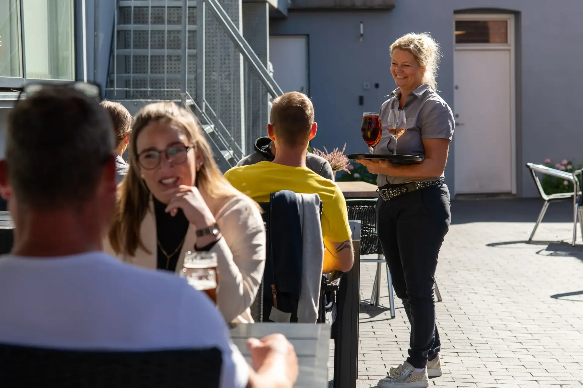 Tjener serverer drinks for gæster på terrassen