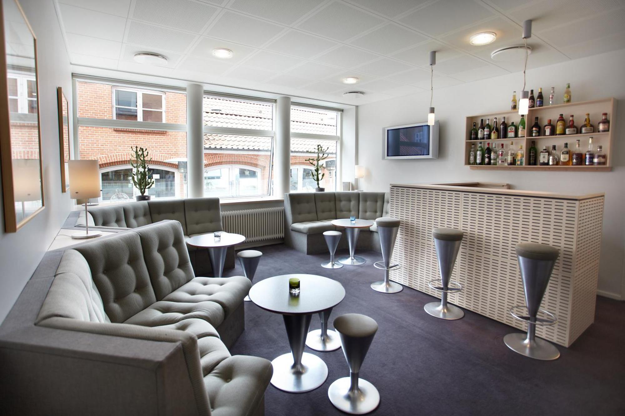 Lounge med grønne sofaer og hotellets bar