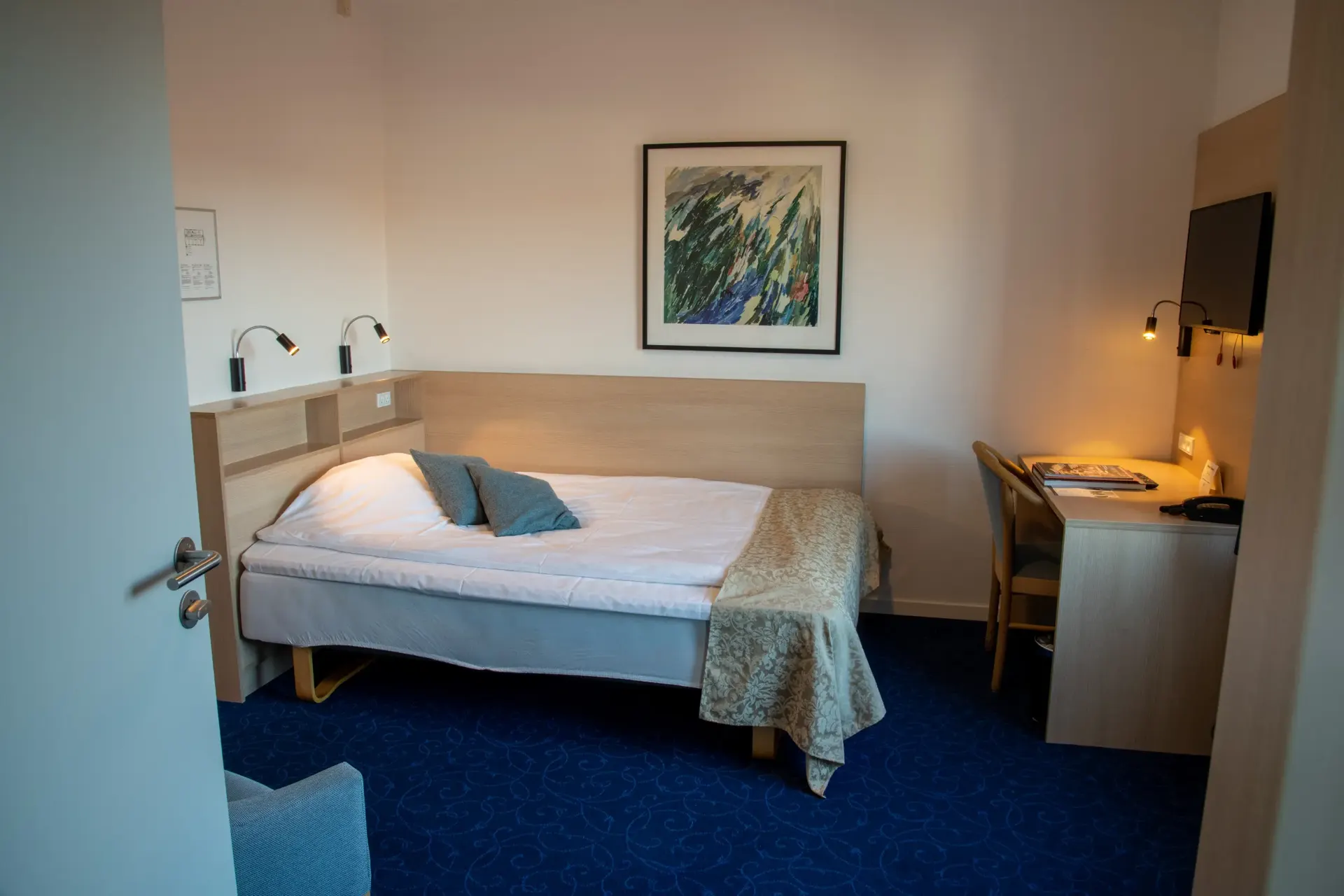 Queen size-værelse med dobbeltseng, høje vinduer og blå gardiner